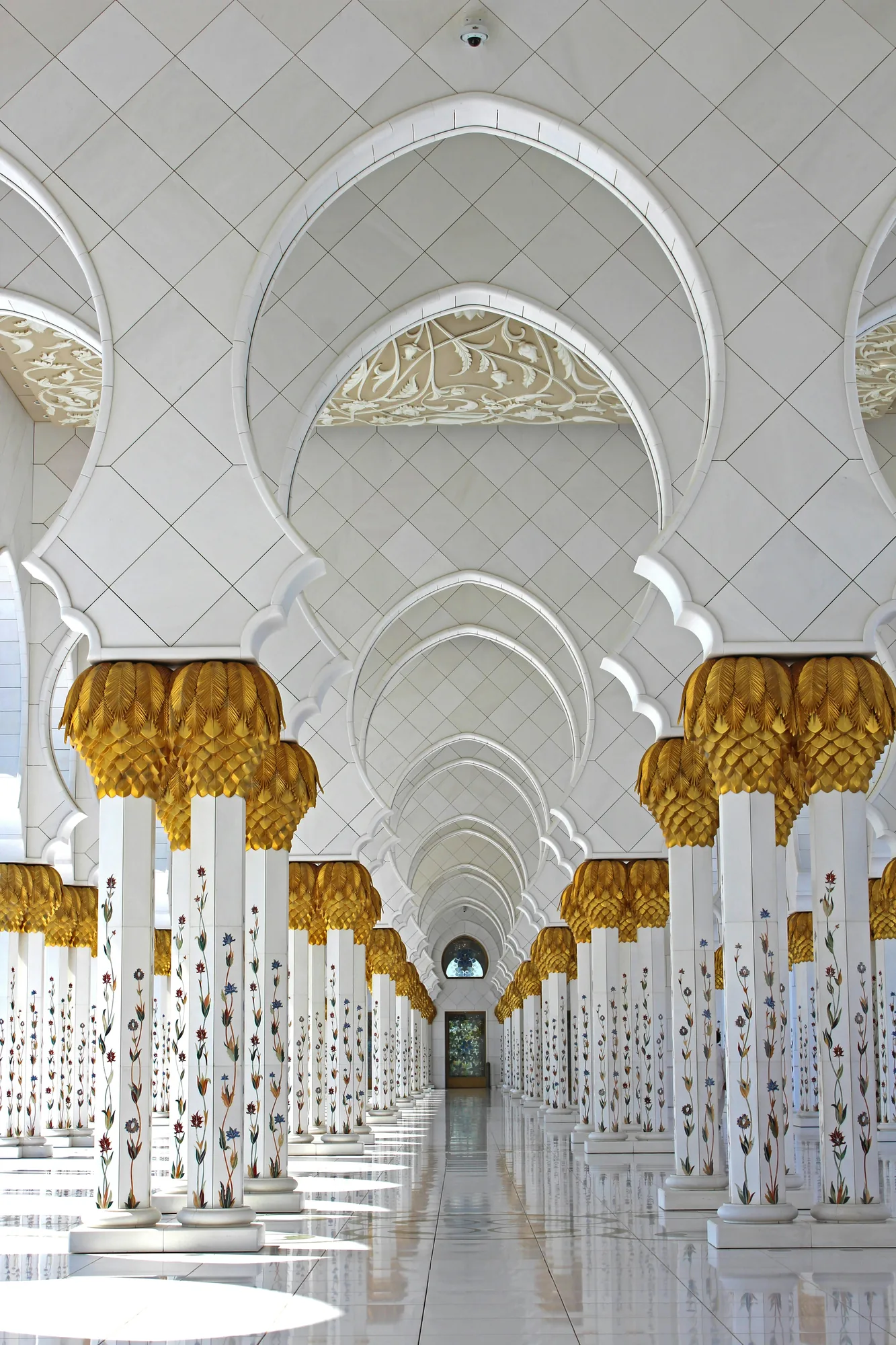 Une colonnade de mosquée, blanche et dorée.