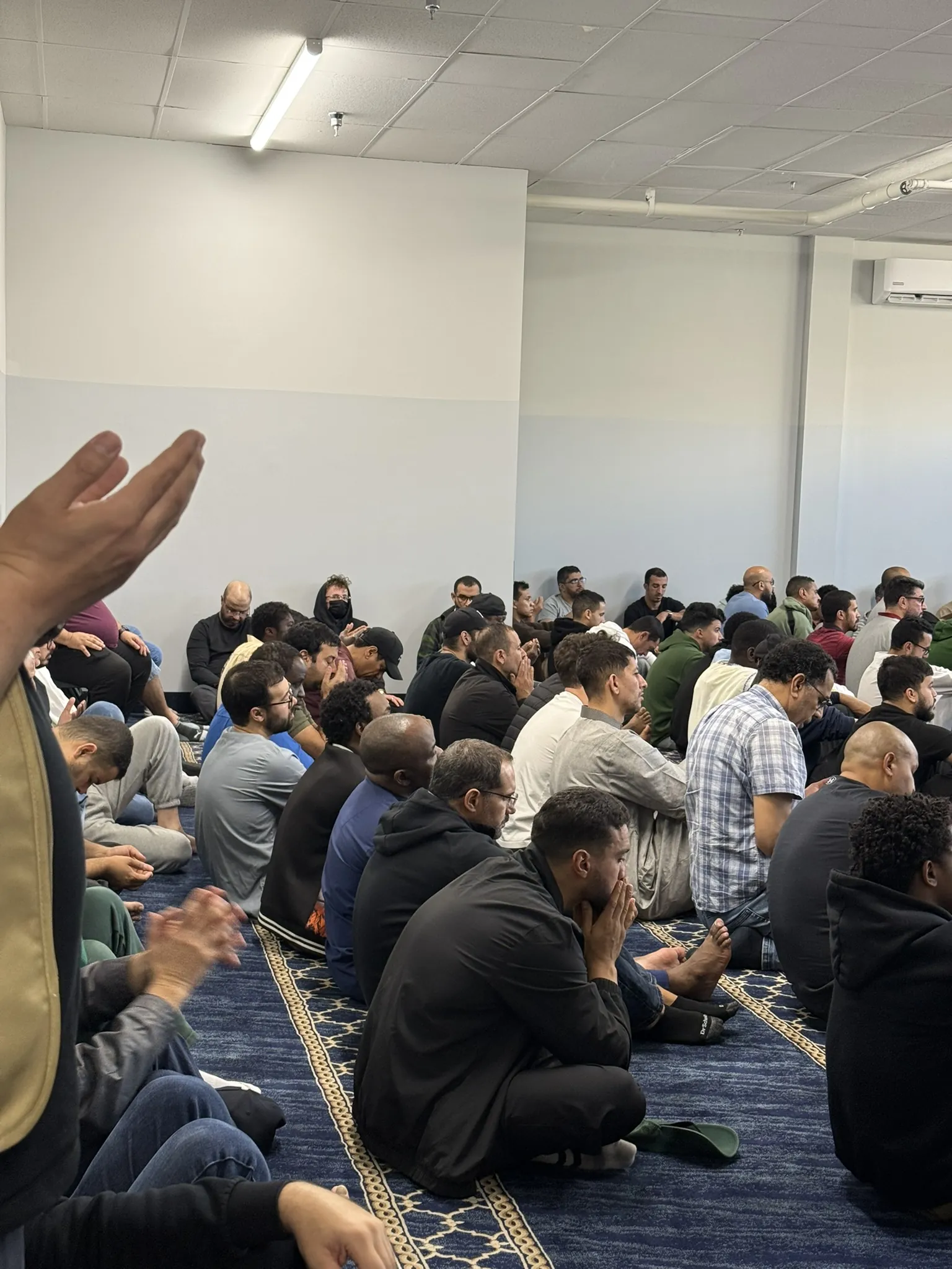 Des mains levées pendant l'invocation, la salle pleine.