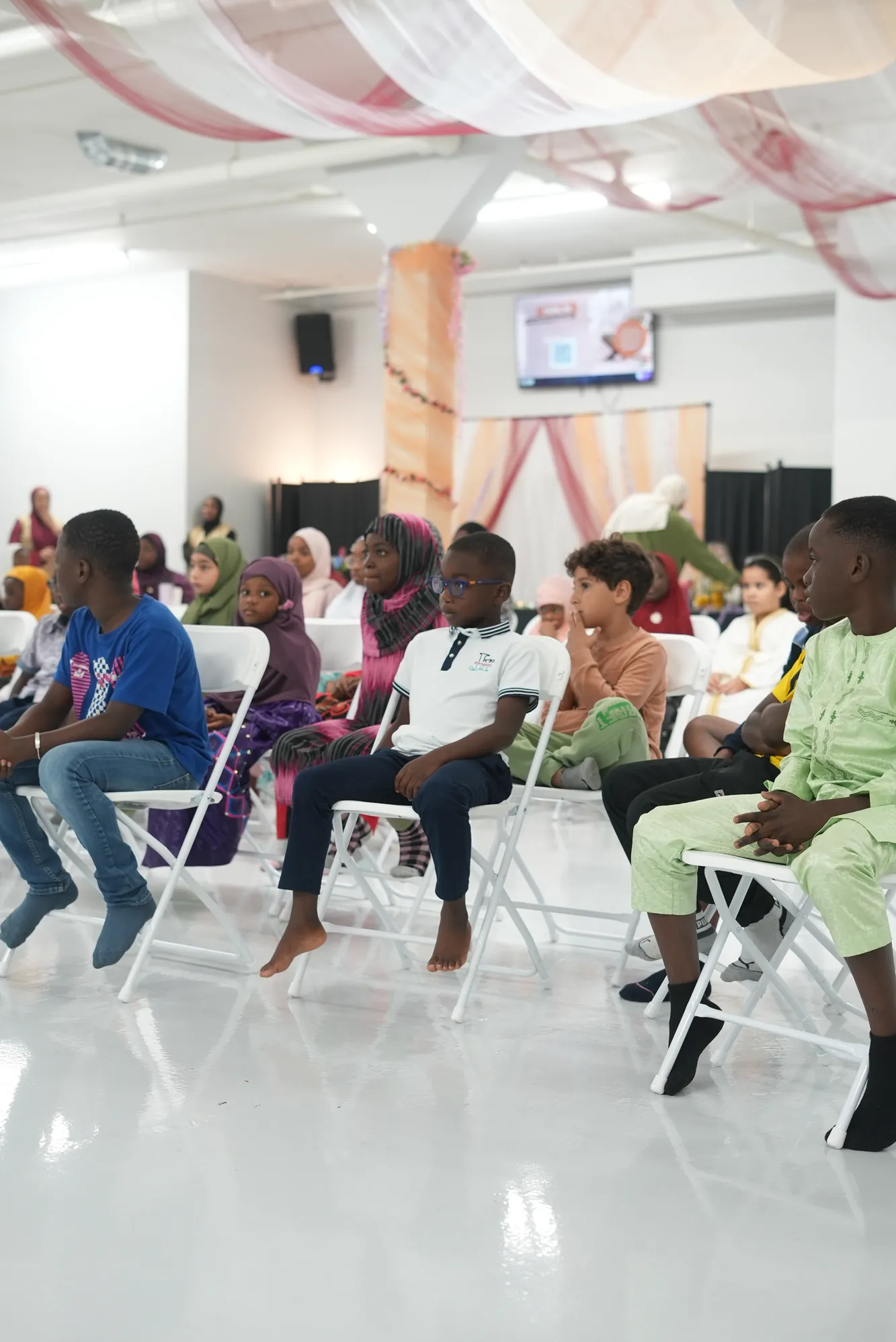 Children sitting in rows in the hall, listening.