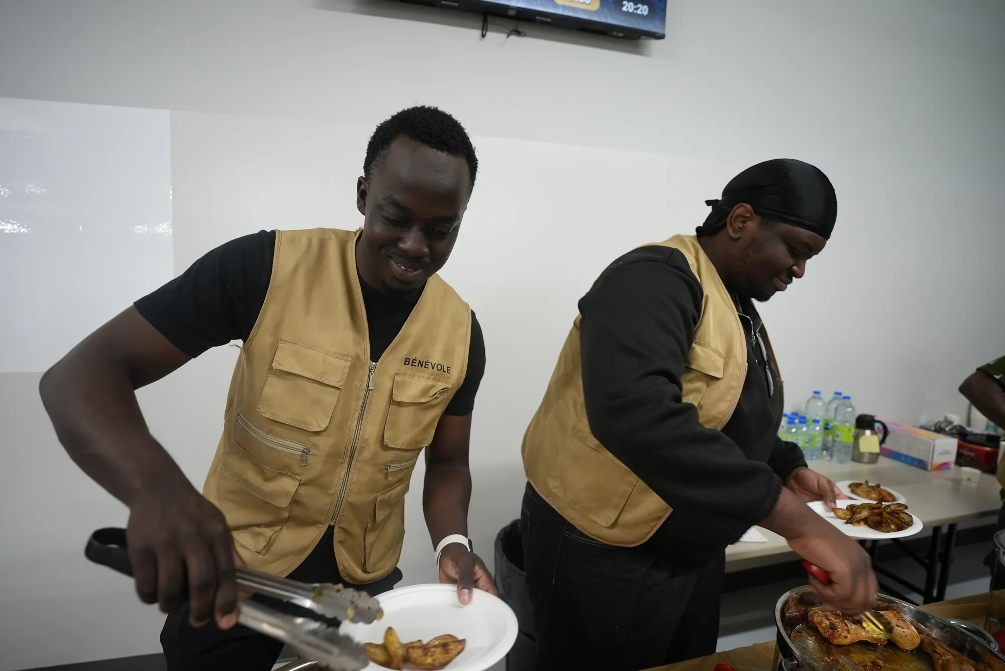Deux bénévoles remplissent des assiettes au buffet.
